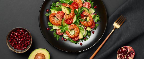 Shrimps salad, avocado, lettuce, cherry tomatoes. Homemade vegetarian shrimp salad. Seafood concept. Mixed leaves, grilled prawn shrimps in plate on black background, banner