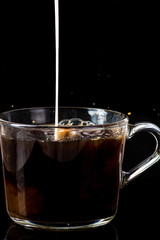 splash of hot instant coffee in a transparent mug on a black background