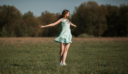 Girl on the field enjoys the spring wind. Fashionable photo. High quality photo.