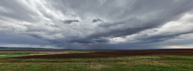 Storm clouds with the rain, panorama of the field against the dark clouds sky