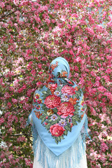 Russian fashionable girl in vintage Pavlovo Posad shawl. Pink flowers of blossoming apple-tree,...