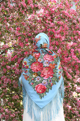 Russian fashionable girl in vintage Pavlovo Posad shawl. Pink flowers of blossoming apple-tree,...