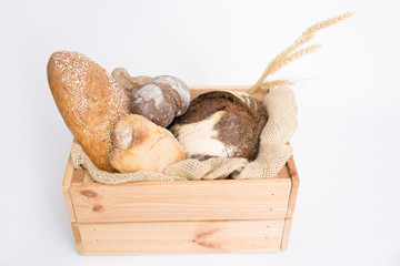 Wooden crate with loafs and buns of freshly baked rye and wheat bread and ears. Isolated object on white background. Baking or traditional bread concept