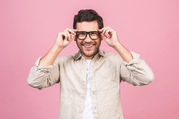 A portrait of young smiling handsome business man in casual shirt isolated on pink background touching his glasses.