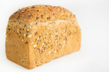 Homemade tasty brick form bread. Crusty whole loaf with cereals, oats, seeds isolated on white background. Studio shot. Selective focus. Side view. Home culinary and baking concept