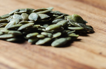 green pumpkin seeds on a wooden board, healthy vegan snack

