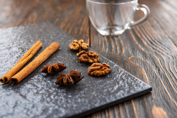 Anise star and cinnamon sticks on a stone tile, go for coffee, in the background an empty glass cup. Coffee seasoning concept.