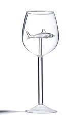 Subject shot of a fantasy wine glass with a long sterm and a crystal shark figure inside. The clear smooth glass is isolated on the white background. 