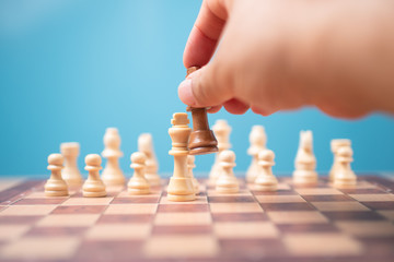 The hand of businessman holding brown king chess and checkmate competitor and win the games. Concept of leadership must have a business strategy and competitor evaluation in competition