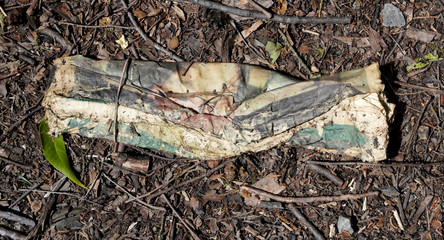 Discarded rolled advertising circular paper deteriorating in dirty alley.    