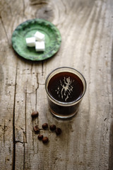 Kaffee in einem Glas und ein Teller mit Würfelzucker auf einem grauen Holztisch. Rustikaler Stil, Espresso