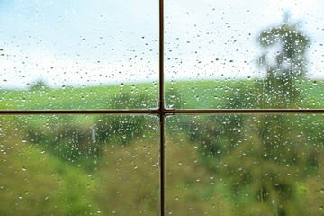 Rainy weather behind wet glass of a house window