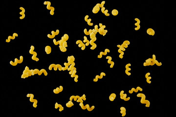 Italian flying raw pasta isolated on black background. macaroni cellentani falling.