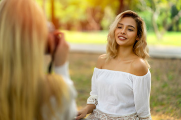 Young caucasian sexy women relaxing in public park. Posting and shooting photo with smiley face in summer from photographer. Cheerful and enjoyable outdoor relaxation and refresh from natural garden