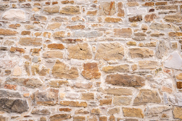 Eine alte verwitterte Steinmauer mit kleinen und großen Steinen als Hintergrund