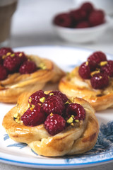 Close-up of French pastry, fresh baked puff pastry buns with raspberries and cappuccino coffee on white table, served breakfast