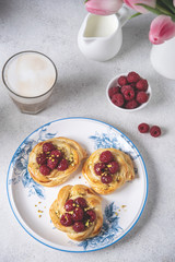 French pastry, fresh baked buns with raspberries and cappuccino coffee on white table