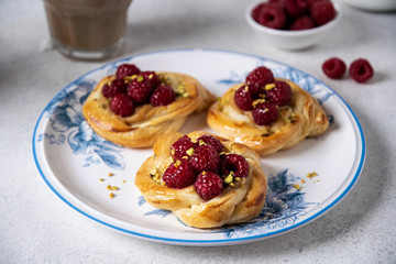 French pastry, fresh baked buns with raspberries and cappuccino coffee on white table