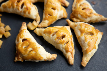apple turnover on a dark concrete table with apple, horizontal view from above, flatlay, free space