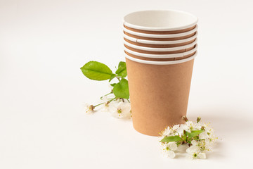 Eco friendly paper dishes. Craft cups, cherry flower. Recyclable tableware for fast food. Copy space. Close up.