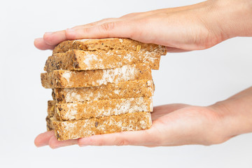 Pile of rye bread slices carrying between female palms. Delicious cereal loaf pieces isolated on white background. Side view. Homemade food and nutrition concept