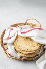 Stack of mexican corn tortillas in a wicker tray covered with kitchen towel