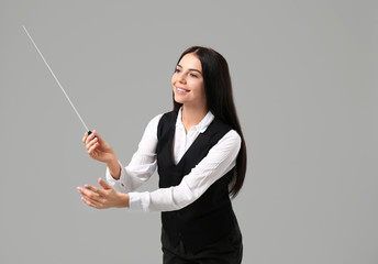 Young female conductor on grey background