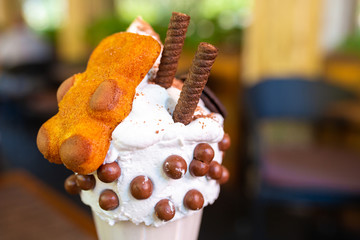 Cool milkshake with cookies and chocolate balls. Milkshake in a glass beaker on a table on a street platform in a cafe. Refreshing summer drinks