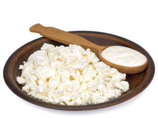 Fresh homemade cottage cheese in a plate and a spoon of sour cream. Grain curd.