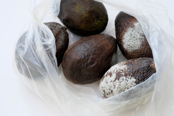 Spoiled avocado fruits in a package. Moldy and rotten avocados. Not the correct storage of products, vegetables. Moldy and rotten avocados