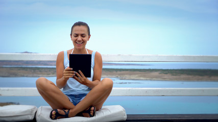 Fototapeta premium Relaxed and cheerful work and vacation outdoor portrait of happy young woman using tablet