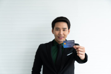 Young asian businessman holding credit card on white background / business concept / payment and expense concept / successful job.