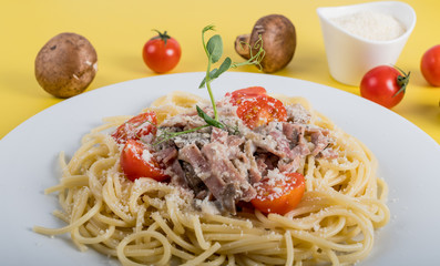 Spaghetti cooked pasta with ingredients on a yellow background. Colorful top and closeup view