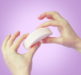 Pink bar of soap in female hands