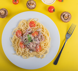 Spaghetti cooked pasta with ingredients on a yellow background. Colorful top and closeup view