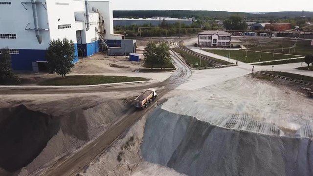 Aerial top view of quarry during work hours. Stock footage. Industrial background with sand quarry and a loaded lorry driving to the factory, professional equipment and machinery.