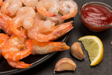 Tiger prawns and shrimp in black plate. Tomato sauce, mint, garlic.