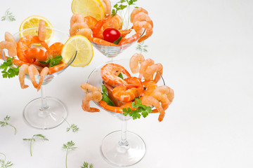Three wine glasses with shrimp lemon and tomato and herbs.