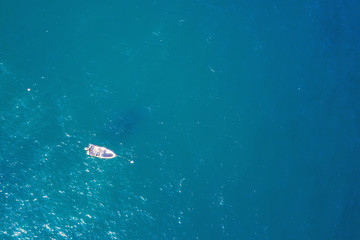 Naklejka na ściany i meble top view of a white boat anchored in the blue sea