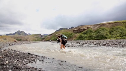 A young tourist crossing a frozen river on the 54 km trek from Landmannalaugar, Iceland