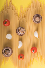 Fototapeta premium Spaghetti pasta with ingredients for cooking pasta on a yellow background. Colorful top and closeup