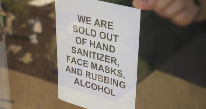 A store owner puts a sign stating they are sold out of hand sanitizer, face masks, and rubbing alcohol. Short supply of necessities was a common sight during the COVID-19 pandemic of 2020.  	