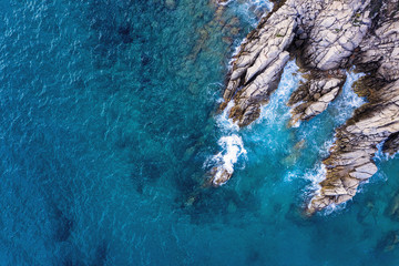 aerial top view of rocky coast with clear blue sea