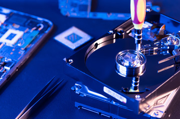 The abstract image of inside of hard disk drive on the technician's desk and a computer motherboard...