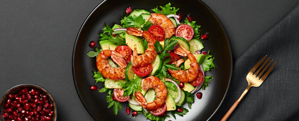 Shrimps salad, avocado, lettuce, cherry tomatoes. Homemade vegetarian shrimp salad. Seafood concept. Mixed leaves, grilled prawn shrimps in plate on black background, banner