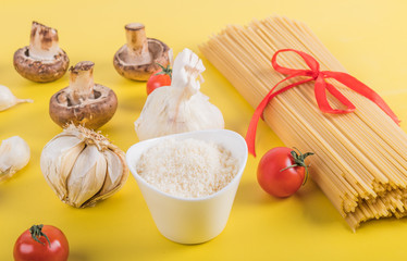 Spaghetti pasta with ingredients for cooking pasta on a yellow background. Colorful top and closeup