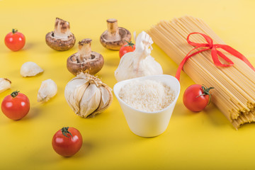 Spaghetti pasta with ingredients for cooking pasta on a yellow background. Colorful top and closeup