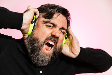 un hombre caucásico con barba de unos 40 años lleva auriculares de color verde en su cabeza.  lo...