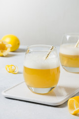 Two whiskey sour cocktails with ingredients, lemon juice, egg white in glass on white. Vertical format.