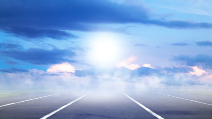 Road with asphalt, sky with clouds and sunlight against the horizon. Summer background